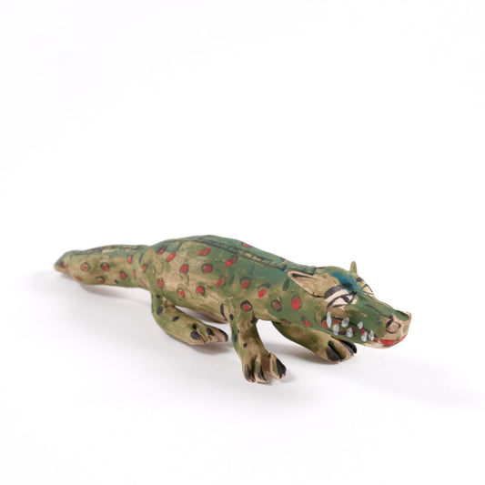 A painted ceramic crocodile whistle in shades of green and brown on a plain white background.