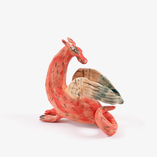 A painted ceramic dragon whistle in shades of orange on a plain white background.