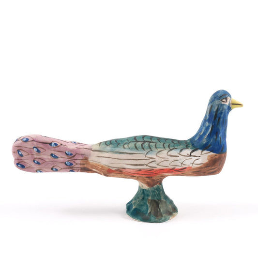 A painted ceramic whistle in shades of blue, pink and green on a plain white background.