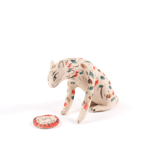 A painted sat ceramic tiger whistle in shades of beige with red, blue and brown spots on a plain white background.