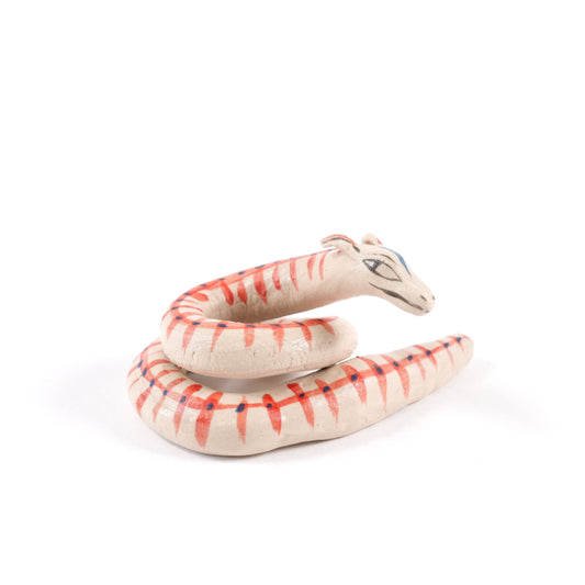 A painted ceramic viper whistle in shades of beige with orange stripes on a plain white background.