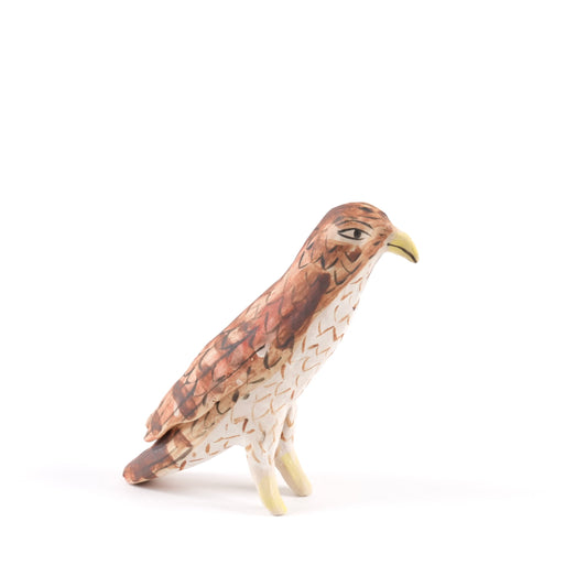 A painted ceramic vulture whistle in shades of brown with a yellow beak on a plain white background.
