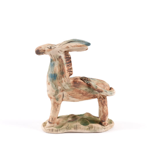 A painted ceramic wild ass whistle in shades of brown and blue standing on a plain white background.