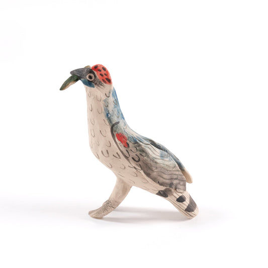 A painted ceramic woodpecker whistle in shades of brown and beige with a red patch on it's head, standing on a plain white background.