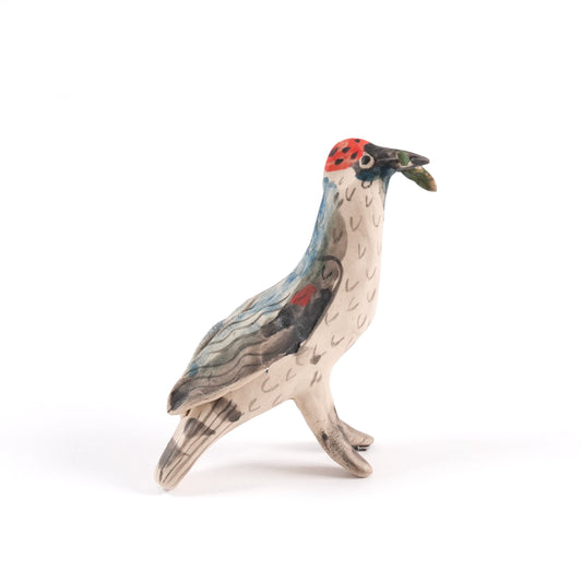A painted ceramic woodpecker whistle in shades of brown and beige with a red patch on it's head, standing on a plain white background.