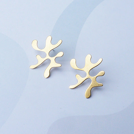 Gold coral-shaped earrings on a light blue background