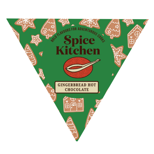 A triangular package design for Spice Kitchen Gingerbread Hot Chocolate, featuring a green background with gingerbread house and cookie illustrations, and the Spice Kitchen logo in the center.
