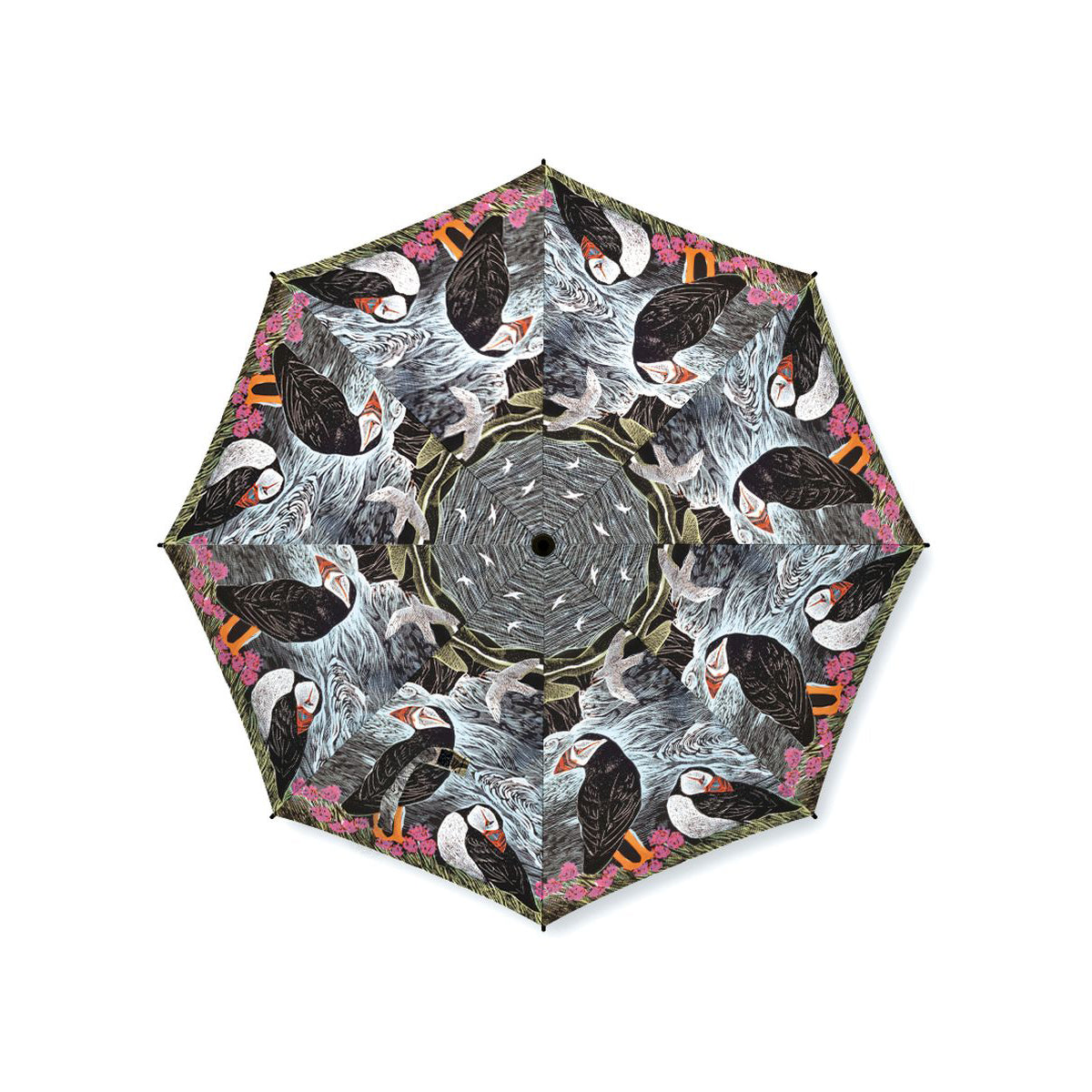 An open umbrella photographed from above on a plain white background, featuring a repeating kaleidoscopic print of puffins in black, white, gray, pink, and orange tones.