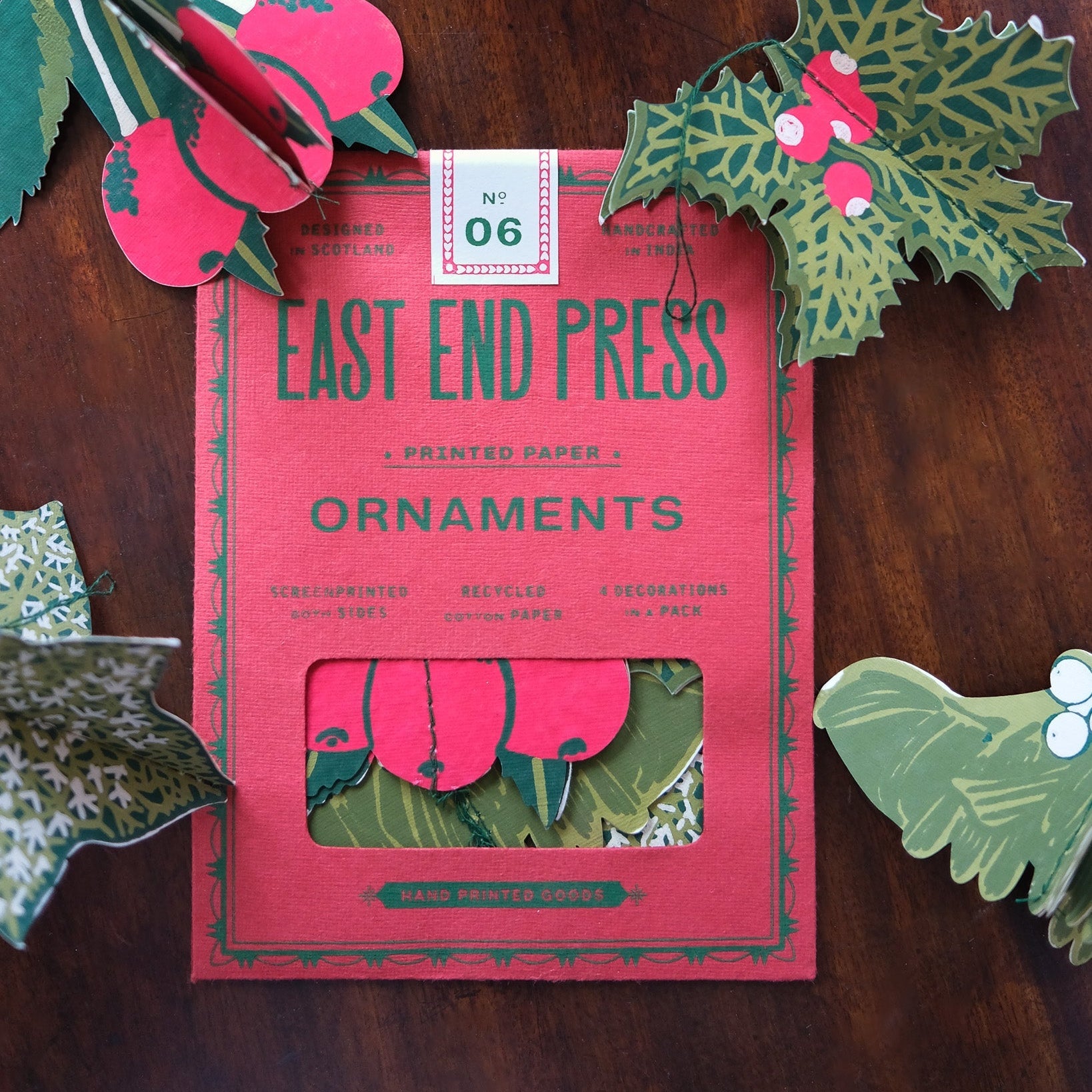 Pack of East End Press ornaments with decorative paper cutouts on a wooden surface