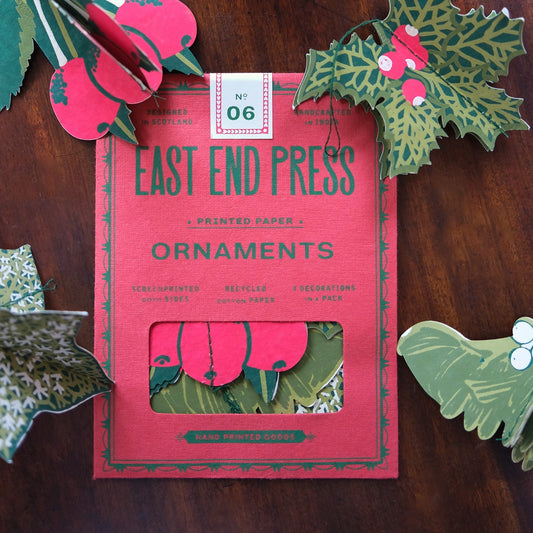 Pack of East End Press ornaments with decorative paper cutouts on a wooden surface