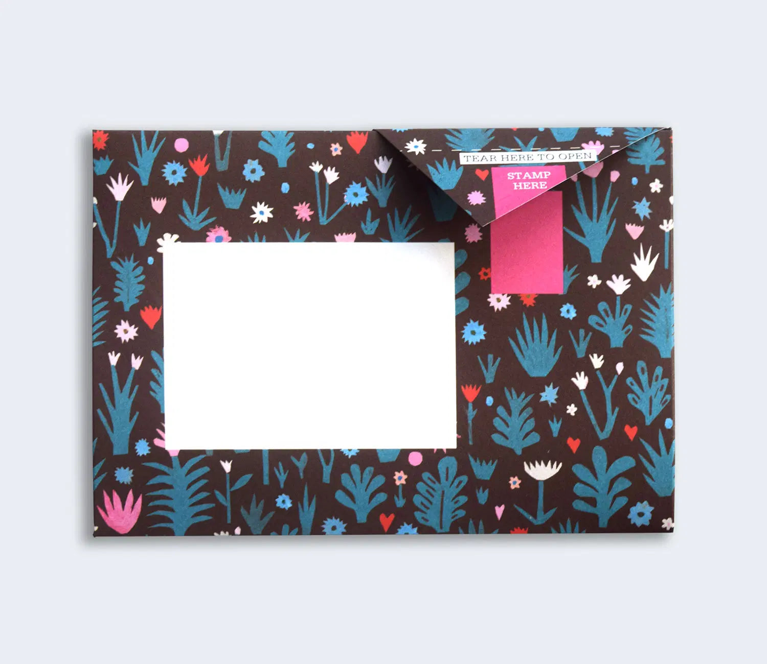 A decorative envelope featuring a brown background adorned with white and blue floral and plant patterns. The top flap has a pink label marked "STAMP HERE" and a blank white space for addressing.