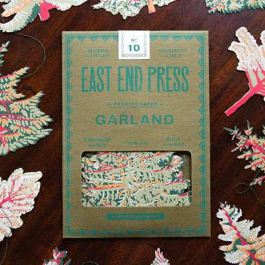Packaging of East End Press Forest Garland with decorative paper trees on a wooden surface