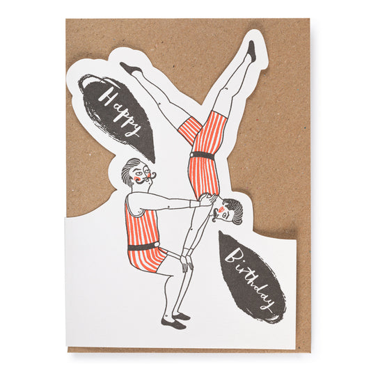 Greeting card with acrobatic illustration and 'Happy Birthday' text on a kraft paper envelope.