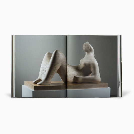Open book with a full bleed image spread featuring stone sculpture of a seated figure on a wooden base.