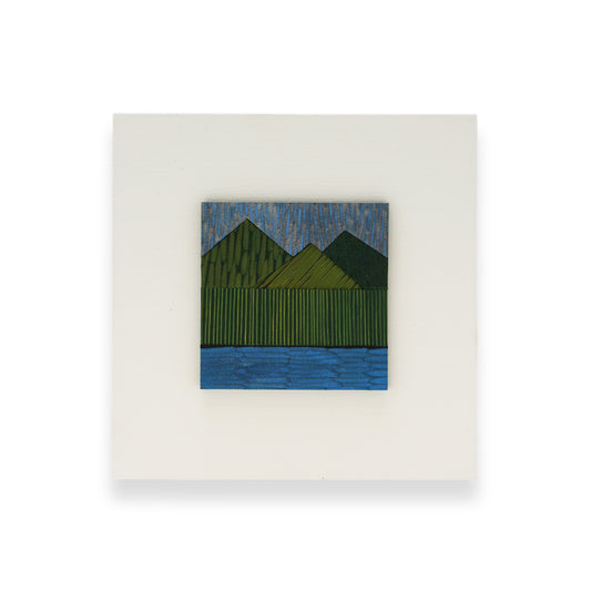 A leather collage mounted on a white MDF back. The collage depicts a landscape; green mountains and a blue body of water.
