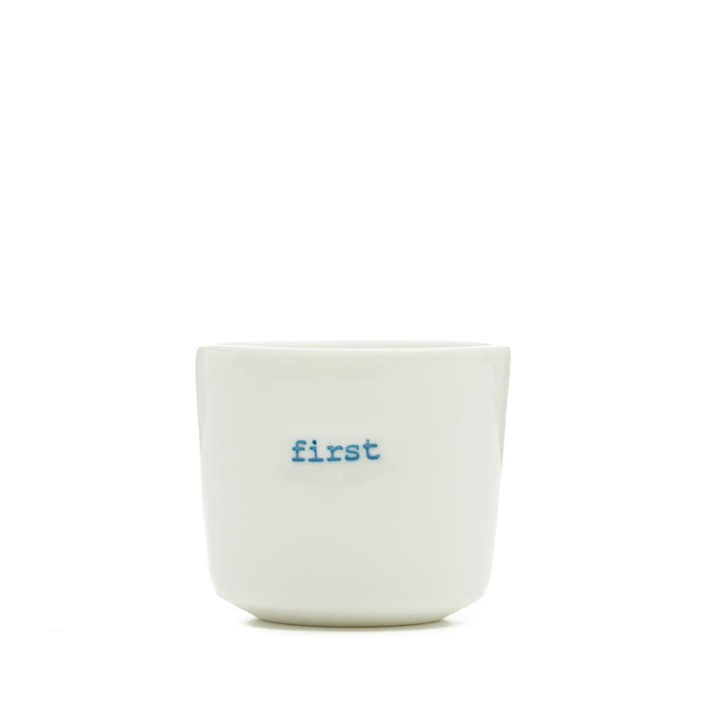 White ceramic egg cup with the word 'first' stamped on the front