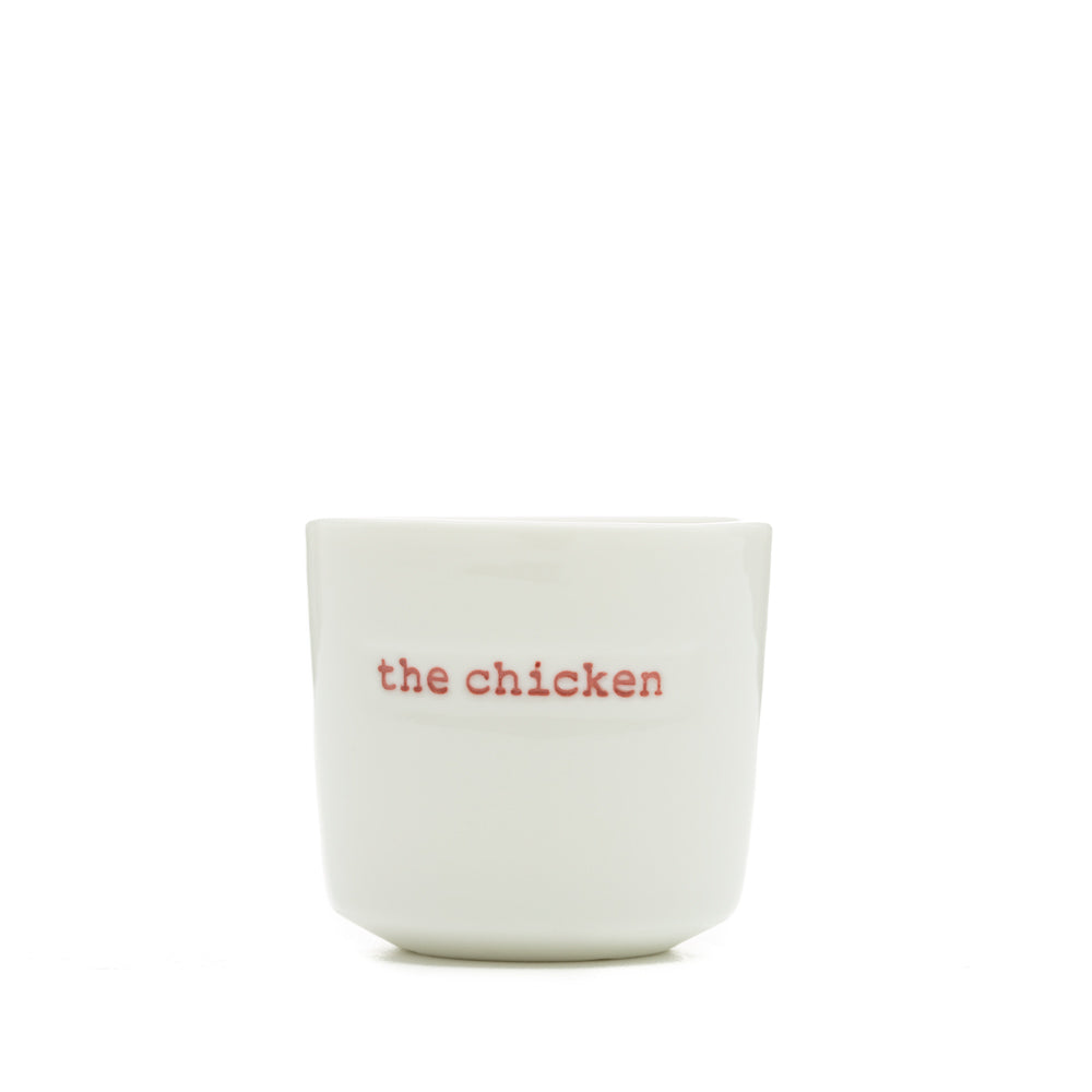 White ceramic egg cup with the words 'the chicken' stamped on the front