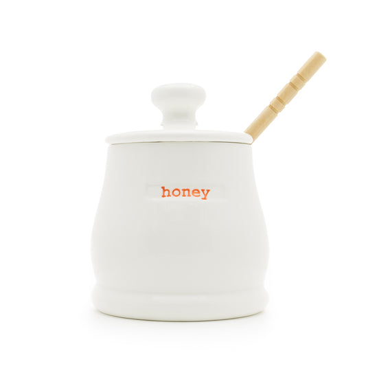 A white ceramic honey pot and lid with 'honey' text on the side, designed by Keith Brymer Jones. The pot comes with a wooden honey dipper.