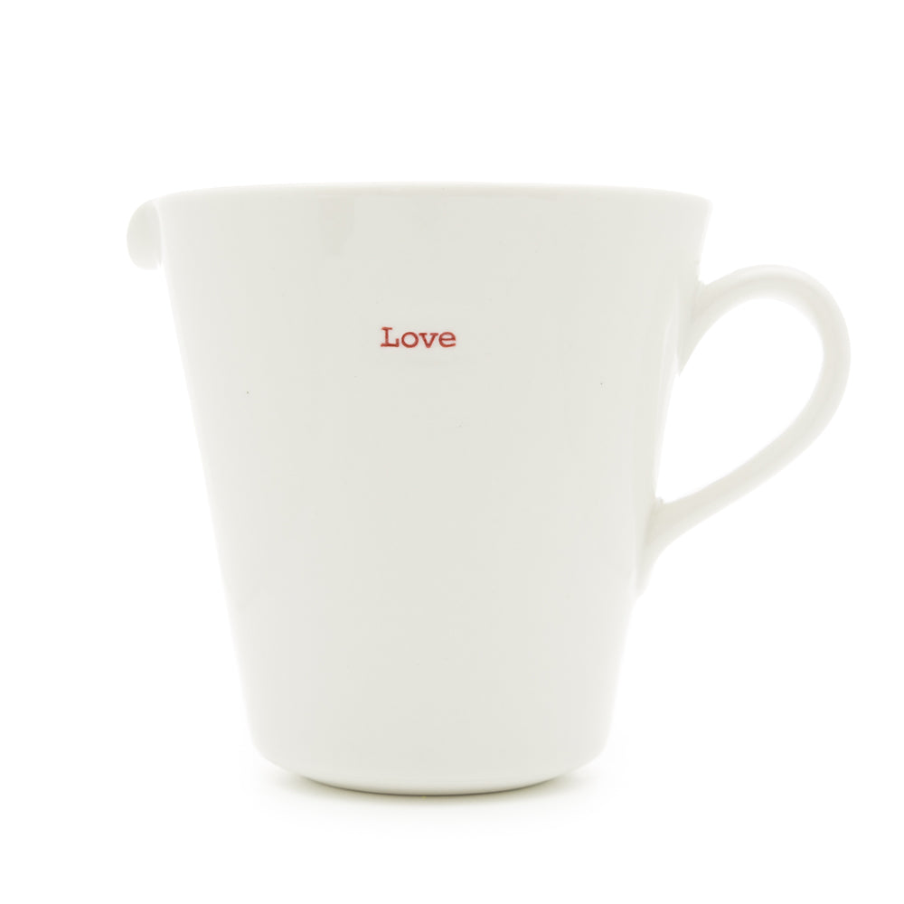 A white ceramic jug with the word 'love' hand-stamped in red typewriter font on the side.