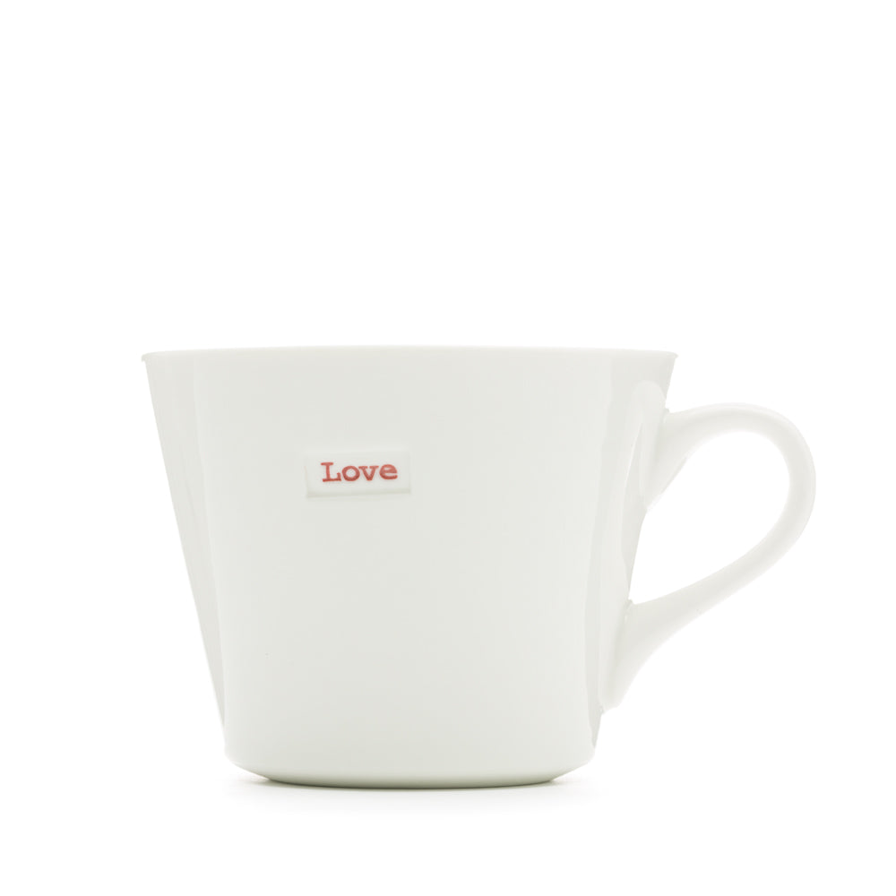 A white Keith Brymer Jones medium bucket mug with the word 'love' stamped in red on the front.