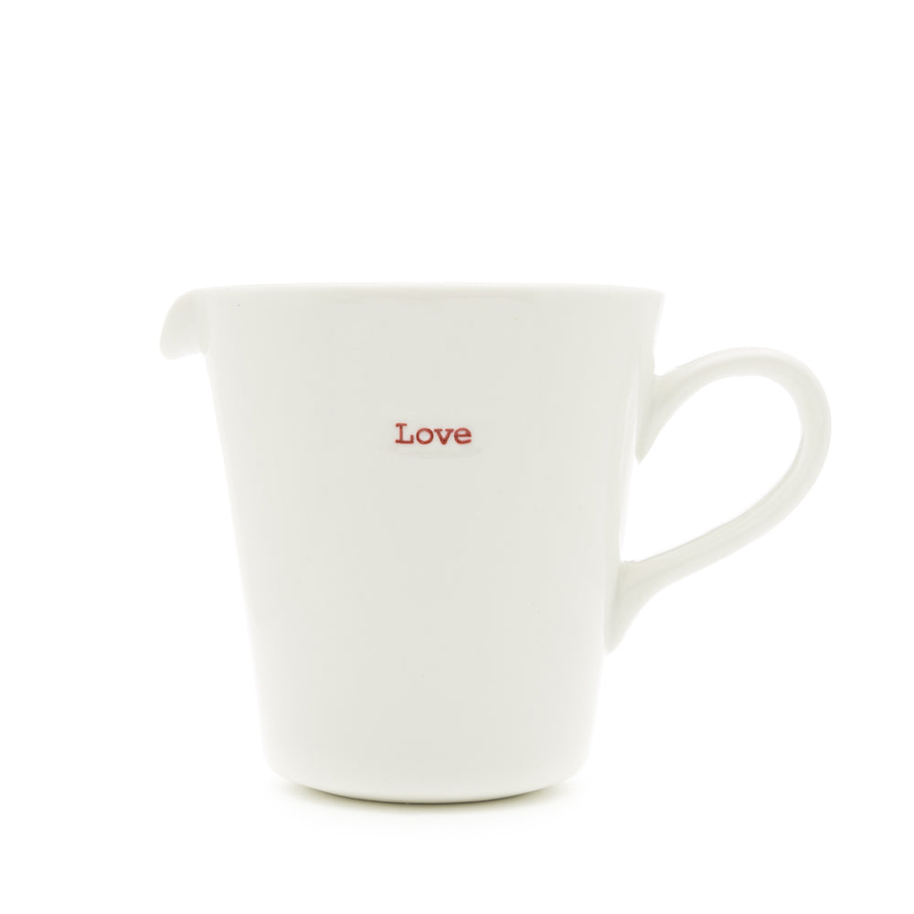 A white porcelain jug with the word 'love' written on it in red, having a pouring spout and handle.