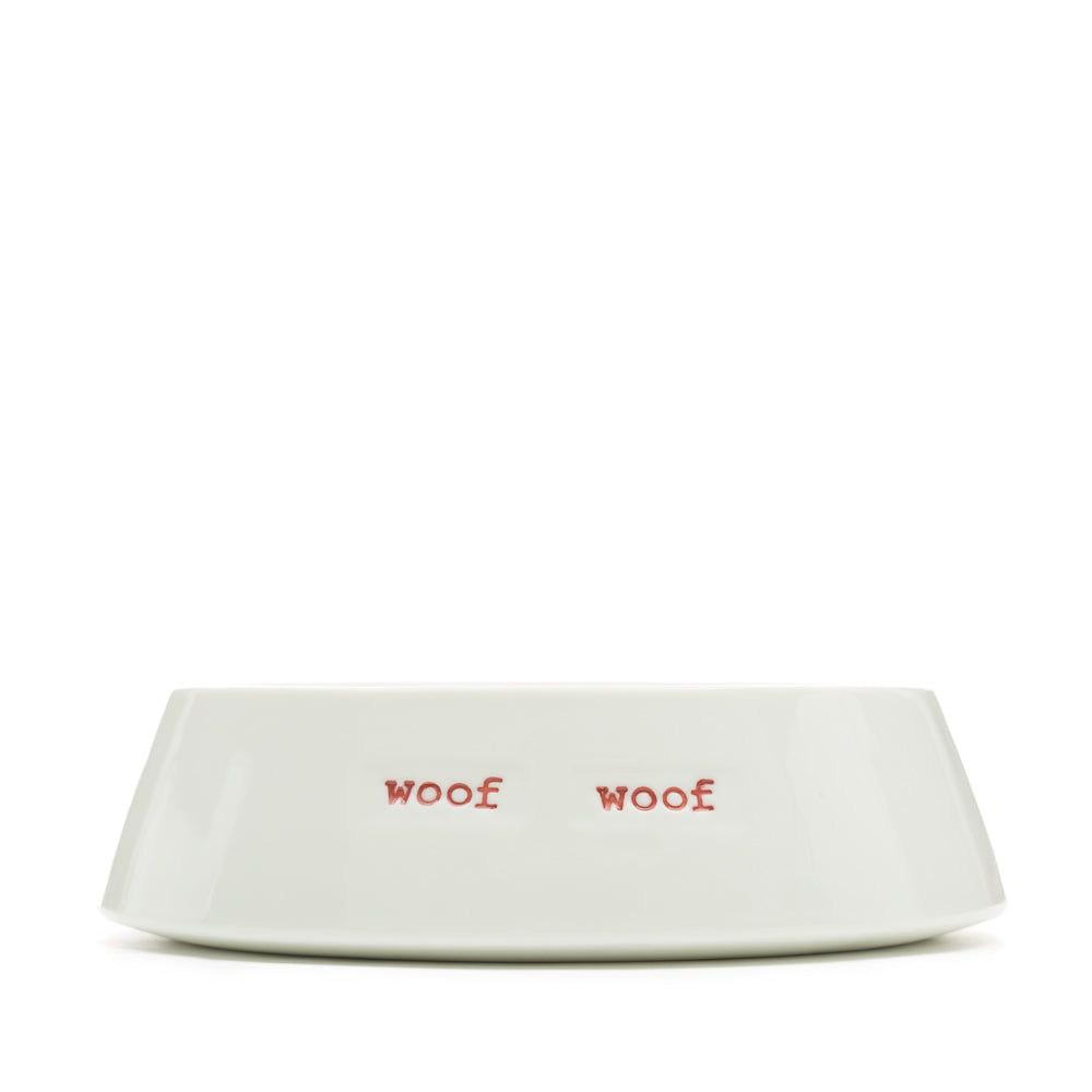 A white ceramic pet bowl with 'WOOF WOOF ' hand-stamped in red.