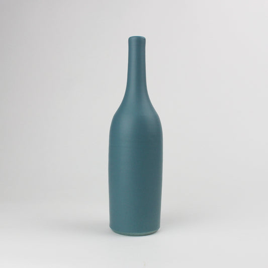 A tall, teal, bottle-shaped earthenware vase with a smooth finish, displayed against a neutral background.
