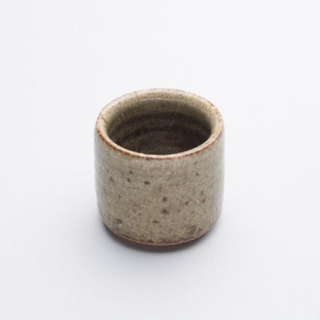 A beige and brown stoneware egg cup with a subtle pattern.