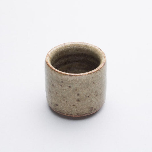 A beige and brown stoneware egg cup with a subtle pattern.