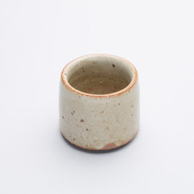 A cream coloured stoneware egg cup, simple in design.
