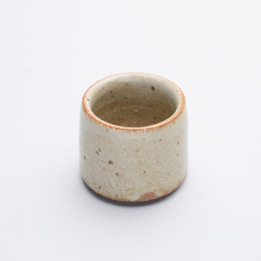 A cream coloured stoneware egg cup, simple in design.