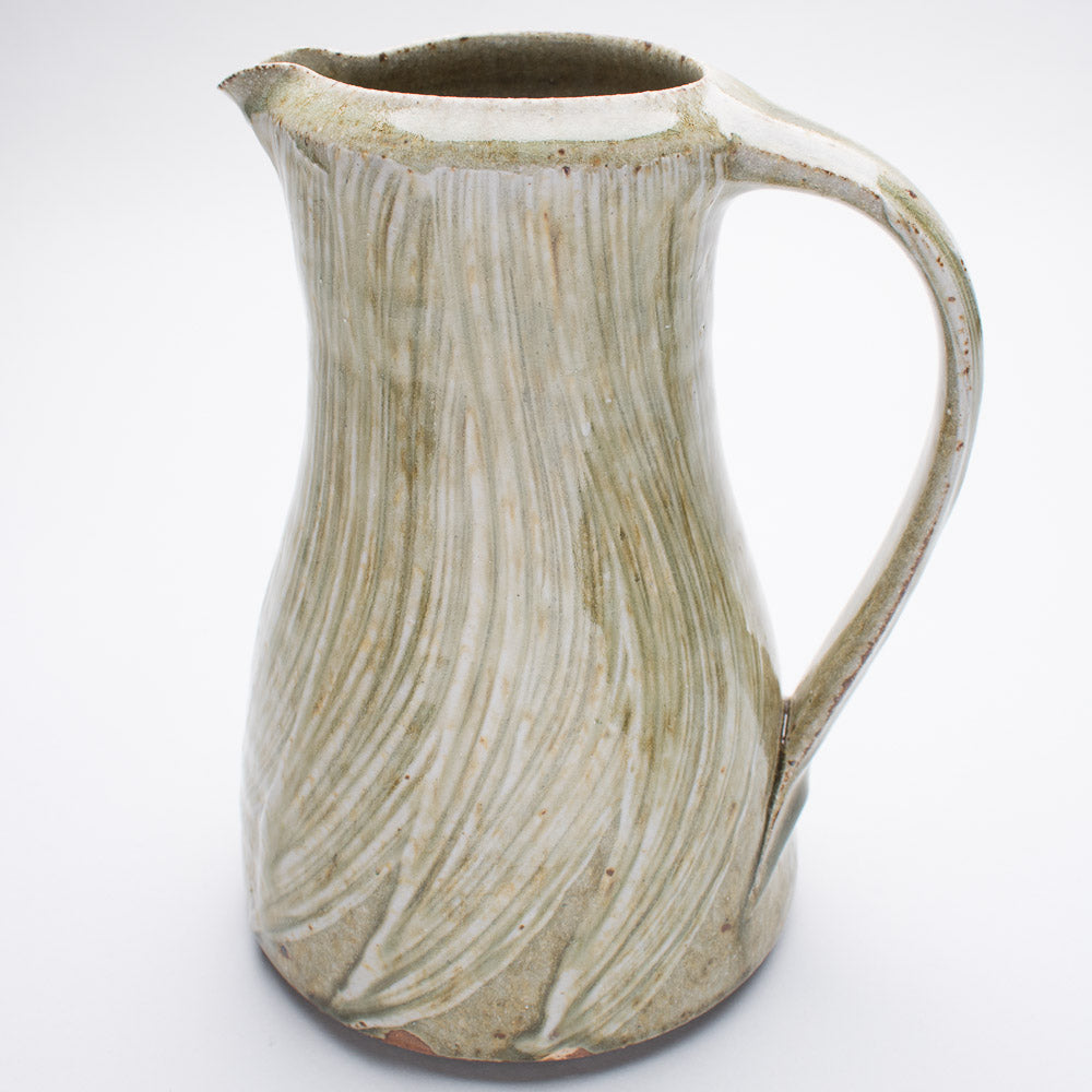 A large ceramic jug in colours of cream and green featuring a brush pattern in the glaze.