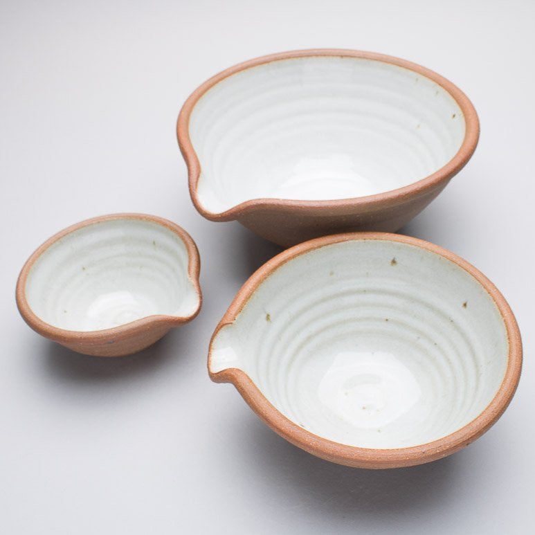 Three ceramic bowls with a brown outer on a white background