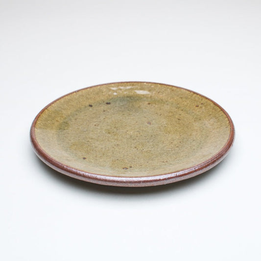 A ceramic plate with a beige center and a greenish-brown rim, with variations in the glaze that give it a unique texture.