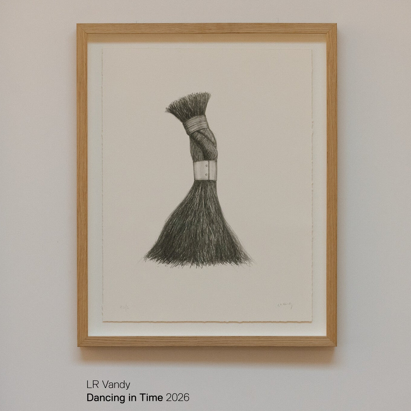 A framed artwork titled "Dancing in Time" by LR Vandy, created in 2026. The piece features a detailed drawing of a brush with a textured bristle head, elegantly tied with a band, displayed against a light background.