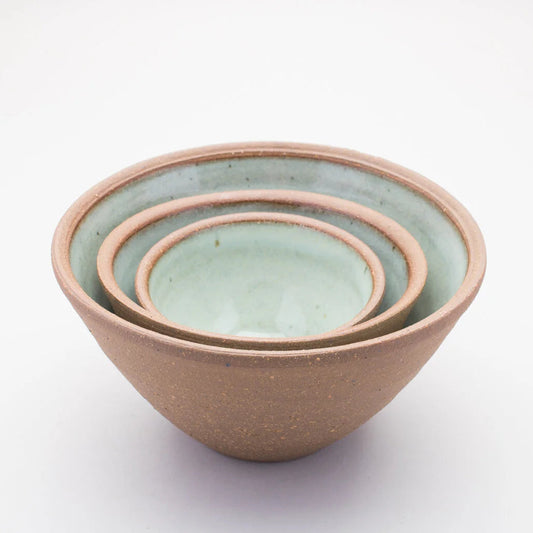 Set of three ceramic bowls stacked inside of each other with a green colour on the inside and a brown outer on a white background