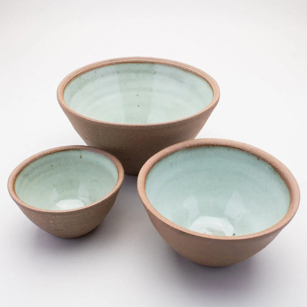 Set of three ceramic bowls with a green colour on the inside and a brown outer on a white background