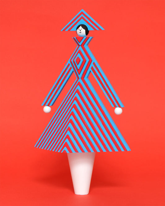 A colourful wooden sculpture with a red and blue stripey 3D top and skirt and a matching headdress with white legs on a plain orange background.