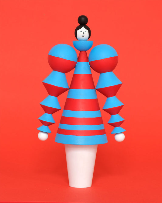 A red and blue wooden figure, featuring a blue and red curved stacked, stripey body with white legs on a plain orange background.