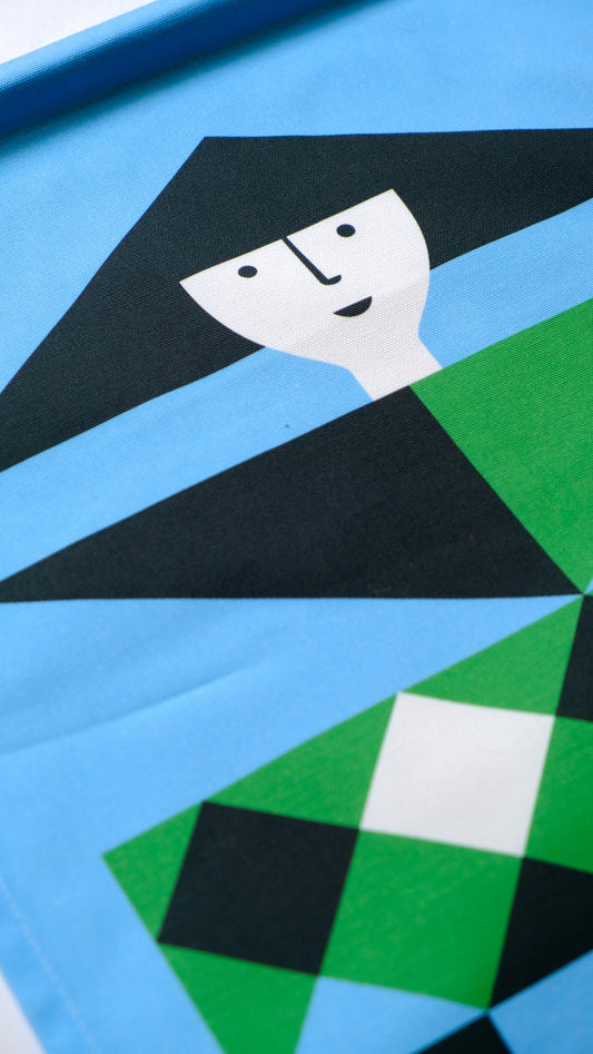 A close up detailed shot of a fabric banner featuring a blue and green geometric figure with black and white accents. 