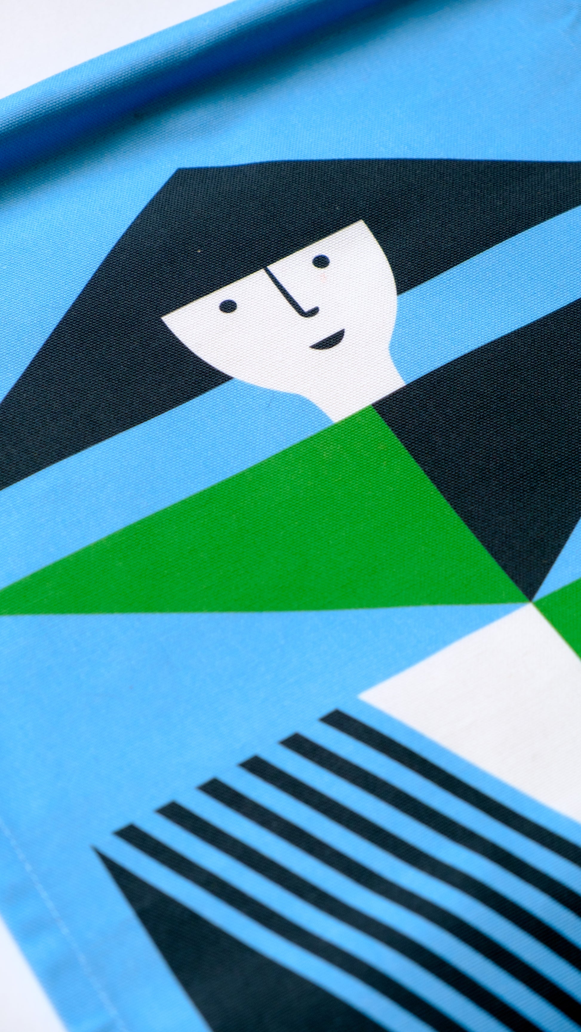 A close up shot of a fabric banner featuring a green and blue geometric figure with black and white accents. 