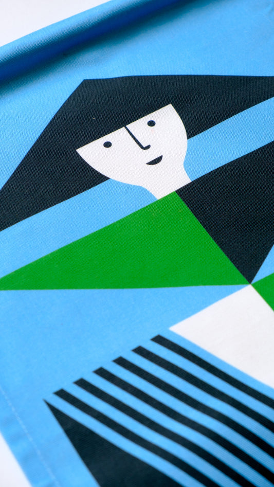 A close up shot of a fabric banner featuring a green and blue geometric figure with black and white accents. 