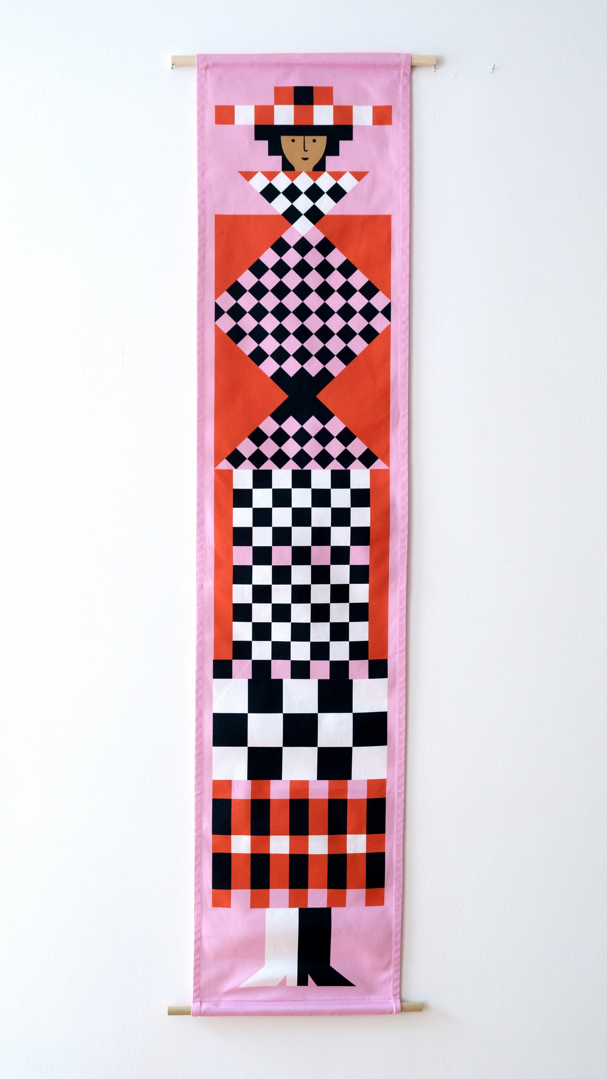 A fabric banner featuring a pink and red geometric figure with black and white accents. 