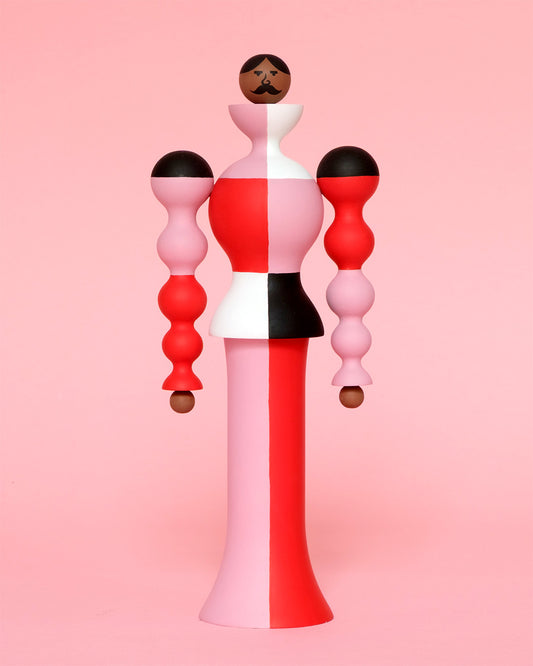 A colourful sculpture with a white, red, black and pink stripey curved body with pink and red legs on a plain pink background.