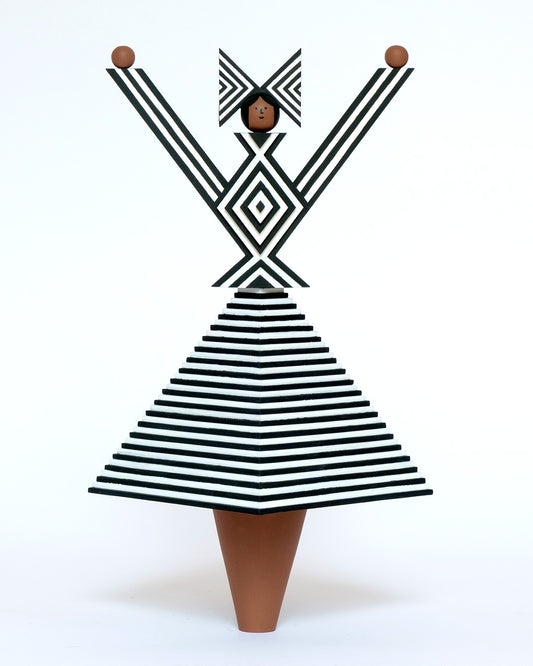 A monochrome wooden sculpture with a black and white stripey 3D top and skirt and a matching headdress with brown legs on a plain white background.