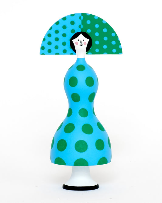 A colourful sculpture with a blue and green spotty body with a matching headdress on a plain orange background.