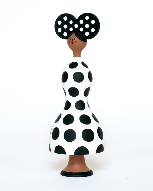 A monochrome sculpture with a black and white spotty body with a matching headdress on a plain white background.