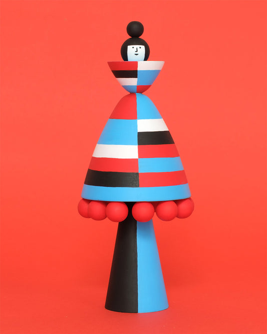 Colourful striped wooden figurine with red, blue, black and white stripes on an orange background.
