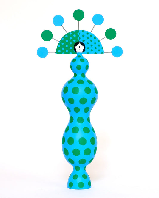 A colourful sculpture with a blue and green spotty body with a matching headdress on a plain white background.