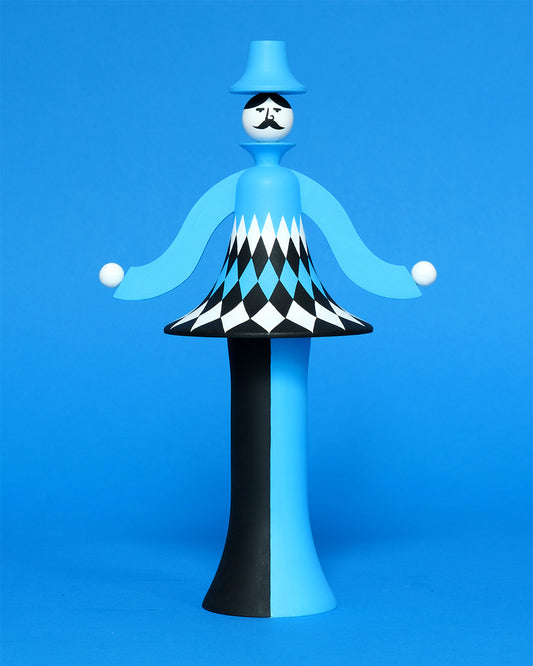 A colourful sculpture with a white, black and blue diamond patterned curved body with blue and black legs and a blue top hat on a plain blue background.
